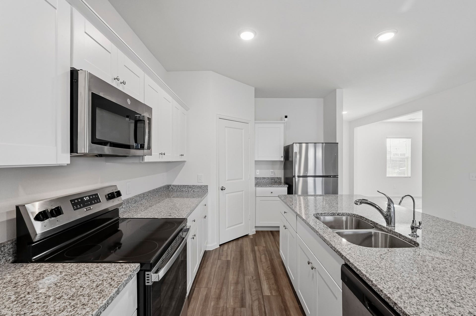 21547 Rolling Streams Drive, New Caney, TX 77357 This bright and modern kitchen features a thoughtfully designed layout with crisp white Shaker-style cabinetry, beautiful speckled granite countertops, and sleek stainless steel appliances. A convenient walk-in pantry provides additional storage space, helping keep the kitchen organized and everyday essentials easily accessible. With ample counter space, abundant cabinetry, and an open connection to the adjoining living areas, this kitchen combines style, functionality, and everyday convenience.