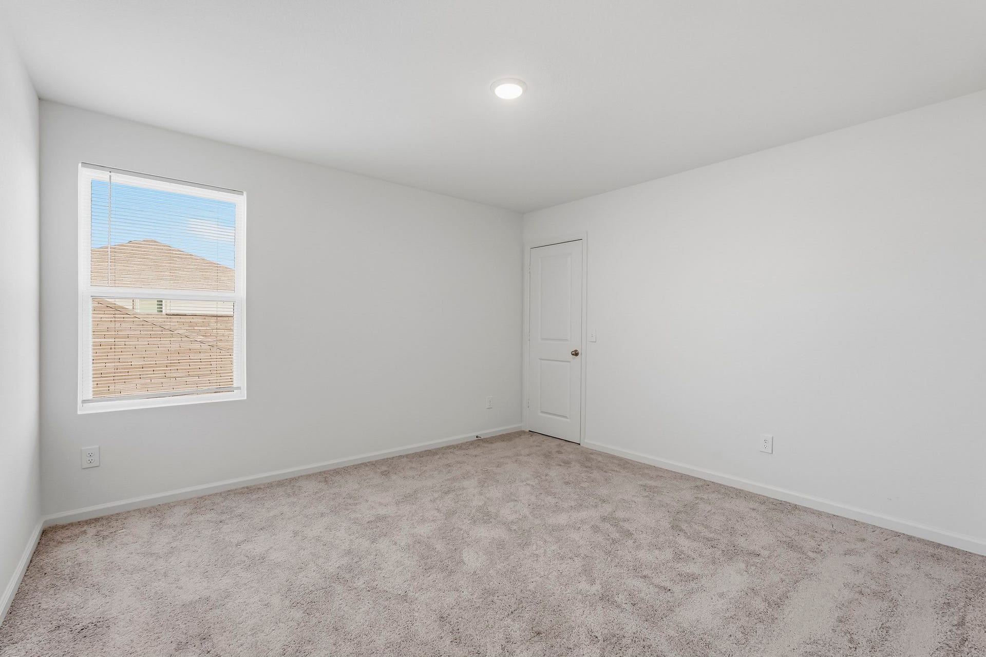 21547 Rolling Streams Drive, New Caney, TX 77357 This bright and spacious secondary bedroom features a clean, modern design with crisp white walls, plush neutral carpeting, and a generous layout. A convenient closet with a classic paneled door adds practical storage, completing this comfortable and functional space.