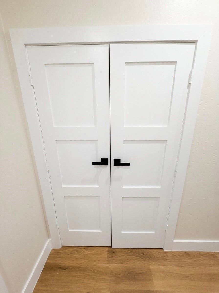 102 Sylvester Road, #C, Houston, TX 77009 Sleek white double doors with modern black handles offer a stylish entrance to laundry room, complementing the warm engineered wood flooring.