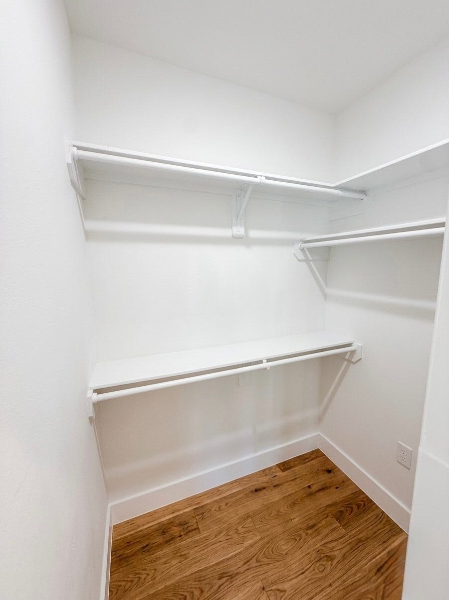 102 Sylvester Road, #C, Houston, TX 77009 Spacious walk-in closet featuring sleek white shelving and ample hanging space, with elegant porcelain flooring for a modern touch.