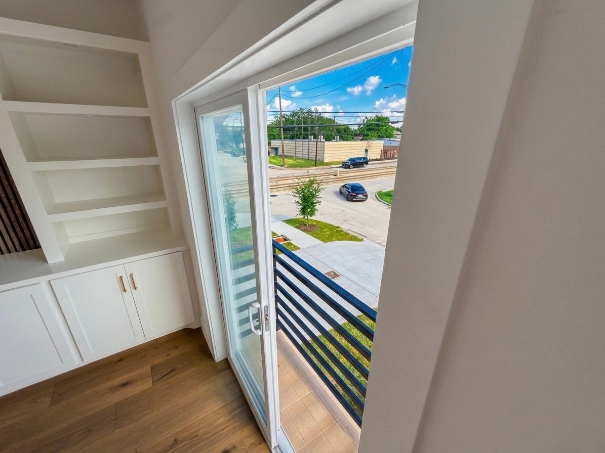 102 Sylvester Road, #C, Houston, TX 77009 Bright room with built-in shelving and hardwood floors, featuring a sliding glass door leading to a balcony with street views.