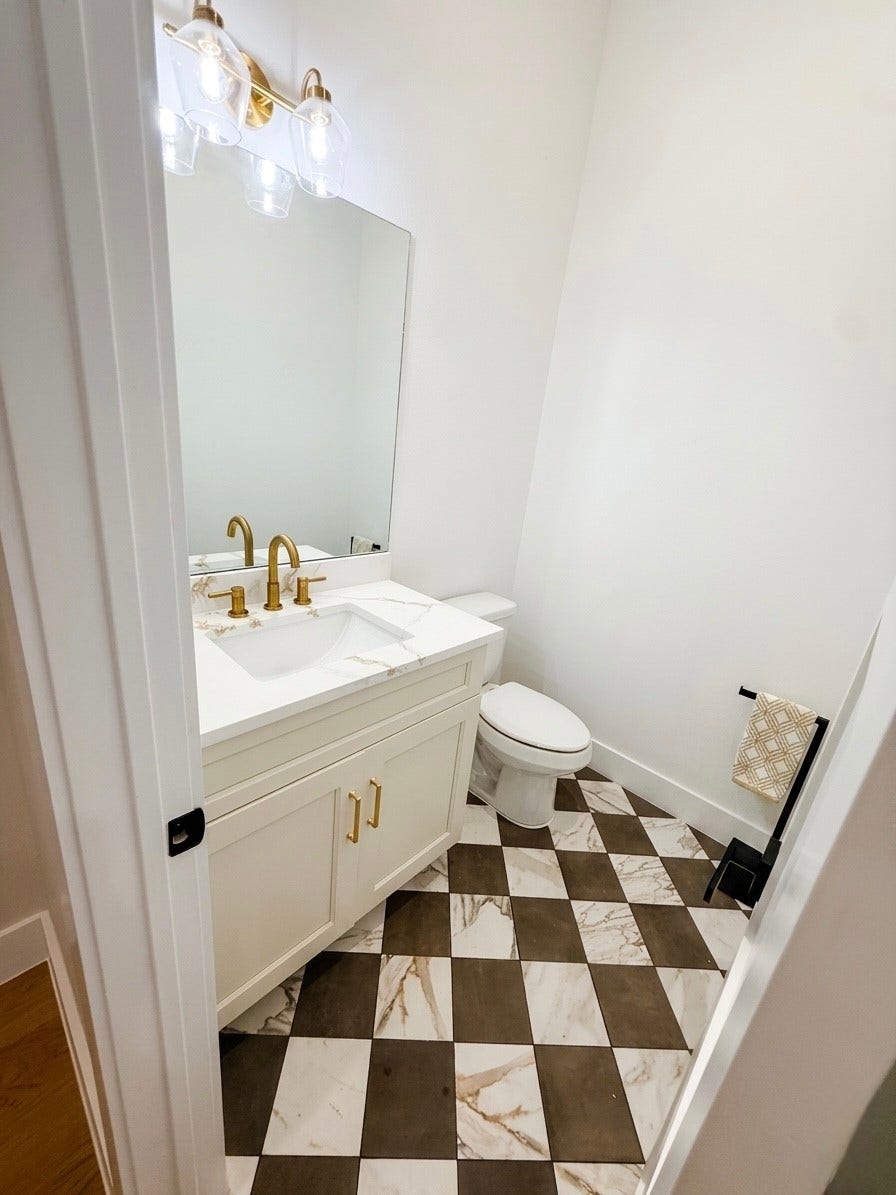 102 Sylvester Road, #C, Houston, TX 77009 Chic bathroom with a modern vanity featuring gold fixtures, a large mirror, and stylish checkered tile flooring.