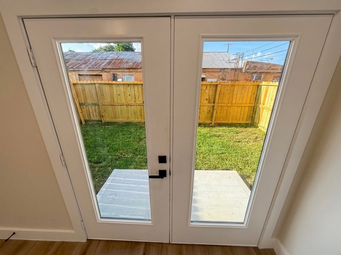 102 Sylvester Road, #C, Houston, TX 77009 Elegant French doors open to a cozy backyard with a wooden privacy fence, perfect for enjoying outdoor relaxation.