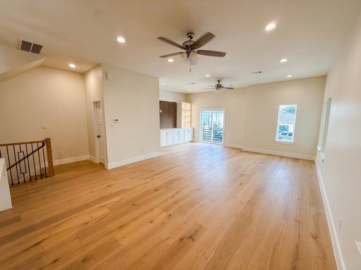 102 Sylvester Road, #C, Houston, TX 77009 Spacious open living area with sleek hardwood floors, recessed lighting, and ceiling fans, leading to a bright space with large windows and double doors opening to a small patio on 2nd floor.