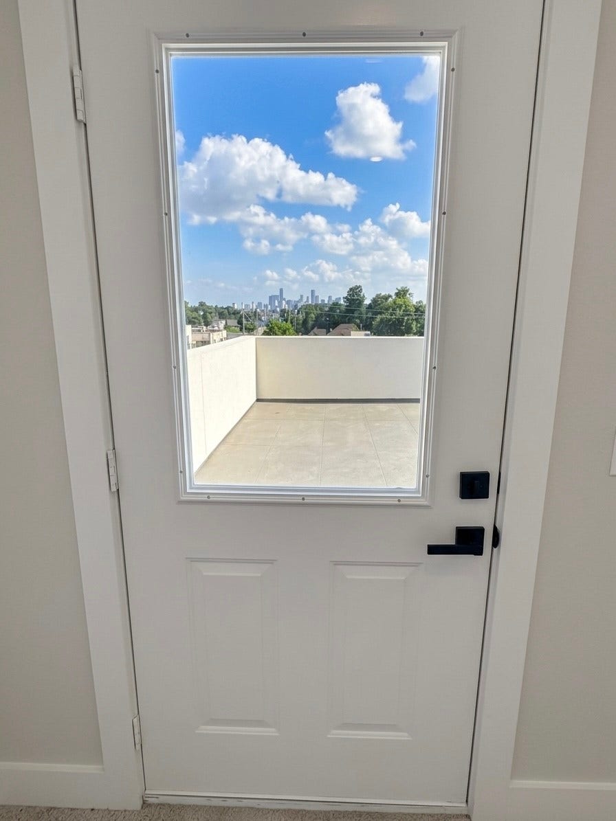 102 Sylvester Road, #C, Houston, TX 77009 Step through a sleek door onto a spacious terrace, offering stunning skyline views under a bright blue sky.