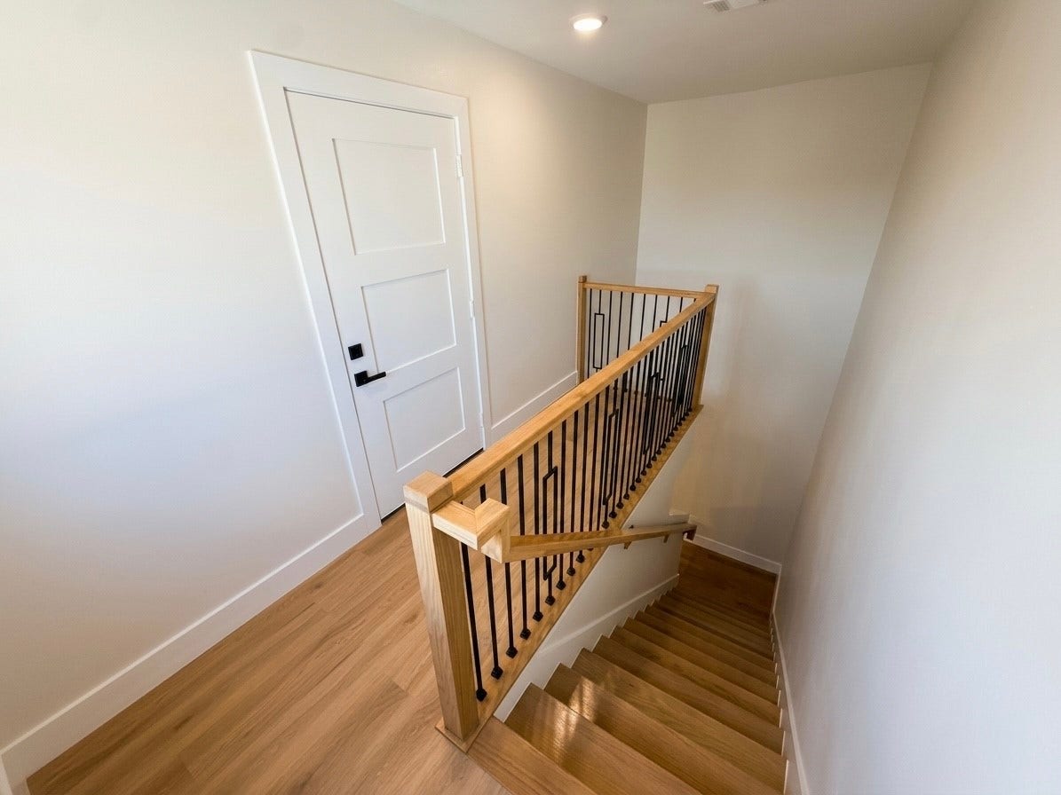 102 Sylvester Road, #C, Houston, TX 77009 Bright and inviting staircase with elegant wooden railings leads to a modern interior door, enhancing the home's contemporary design.