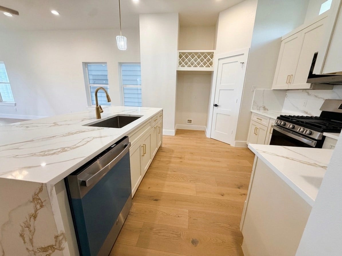 102 Sylvester Road, #C, Houston, TX 77009 Elegant kitchen featuring sleek quartz countertops, modern stainless steel appliances, and light engineered wood flooring.