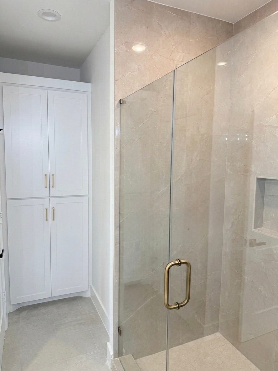 102 Sylvester Road, #C, Houston, TX 77009 Elegant bathroom featuring a spacious glass-enclosed shower with stylish tile work and ample storage in the sleek white cabinetry.