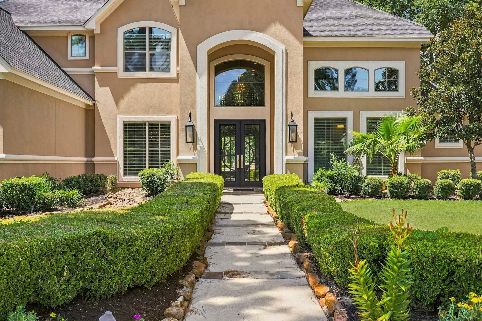 7611 Kings River Lane, Humble, TX 77346 Elegant front entry featuring double steel entry doors, traditional gas lanterns and distinctive architectural detailing that complements the home's stately exterior.