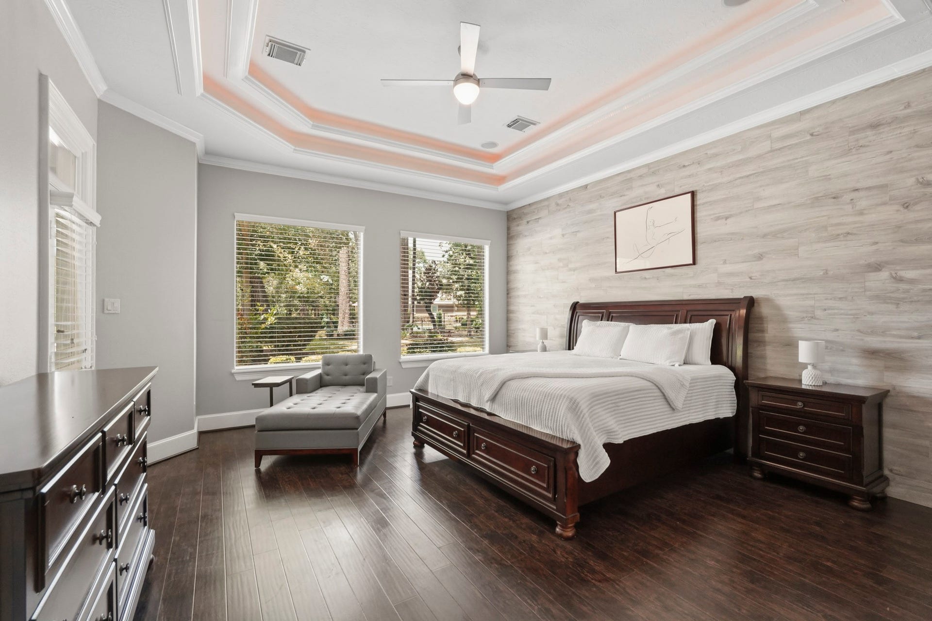 7611 Kings River Lane, Humble, TX 77346 Spacious primary suite featuring rich wood flooring, a dramatic tray ceiling with accent lighting and direct access to the covered outdoor living area, pool and built-in outdoor cooking station.