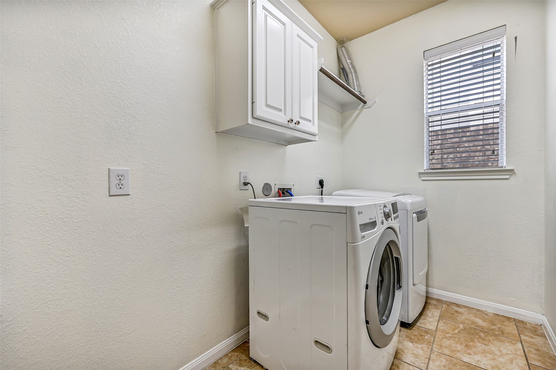 2508 Rockygate Lane, Friendswood, TX 77546 Conveniently located on the first floor, the utility room offers tile flooring, upper storage cabinetry, and a built-in shelf for laundry essentials. A window provides natural light to brighten daily chores, while additional floor space allows room for a bonus refrigerator or freezer, keeping extra storage conveniently tucked away from the main living areas.