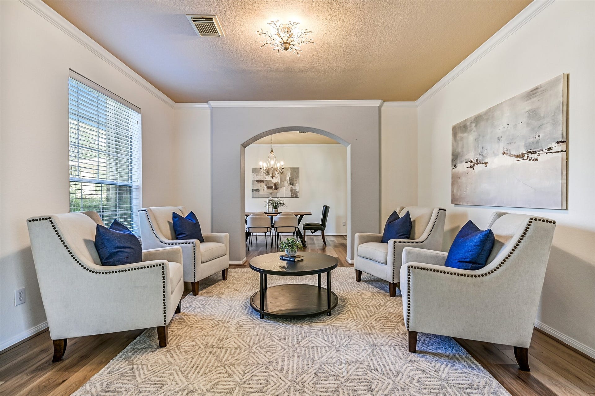 2508 Rockygate Lane, Friendswood, TX 77546 A wide arched entrance from the foyer welcomes guests into this versatile formal living room featuring fresh neutral paint, elegant crown molding, a stylish updated light fixture, and newly installed luxury vinyl plank flooring. A large front-facing window fills the room with natural light, creating an inviting space for conversation, reading, or entertaining.