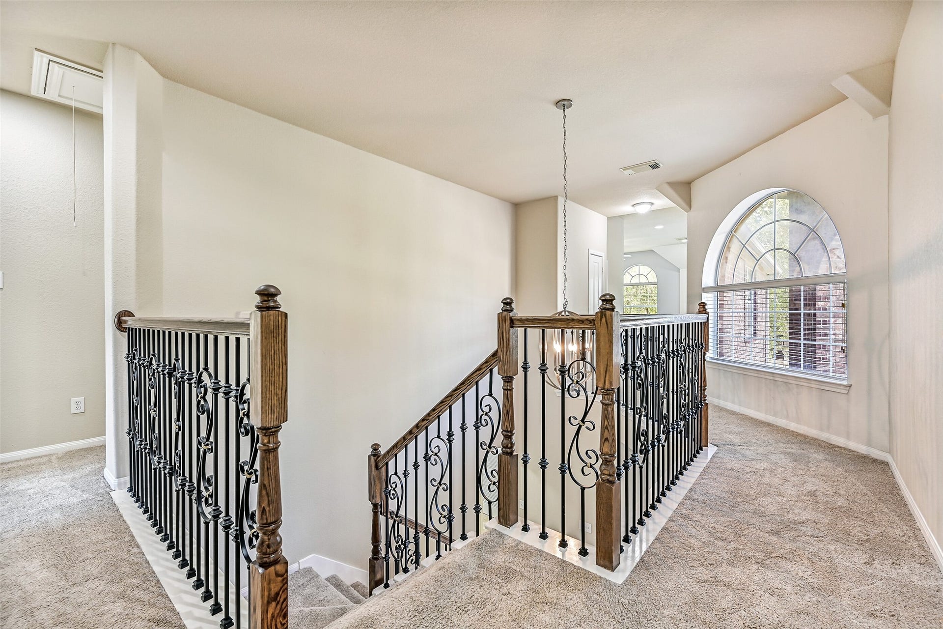2508 Rockygate Lane, Friendswood, TX 77546 Ascend the sweeping split staircase to an impressive second-floor overlook featuring plush new carpet, decorative wrought iron balusters, and views of the soaring foyer below. A large arched window floods the landing with natural light, creating an airy transition to the oversized game room, secondary bedrooms, and the private owner's retreat beyond.