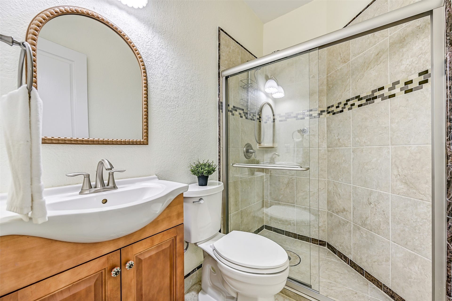 2508 Rockygate Lane, Friendswood, TX 77546 Conveniently located near the garage entrance and adjacent to the study, this full bathroom is ideal for both guests and everyday use. The space features tile flooring, a vessel sink atop a raised-panel vanity, a framed mirror, and a walk-in shower with a sliding glass enclosure, decorative accent tile, and a full tile surround.