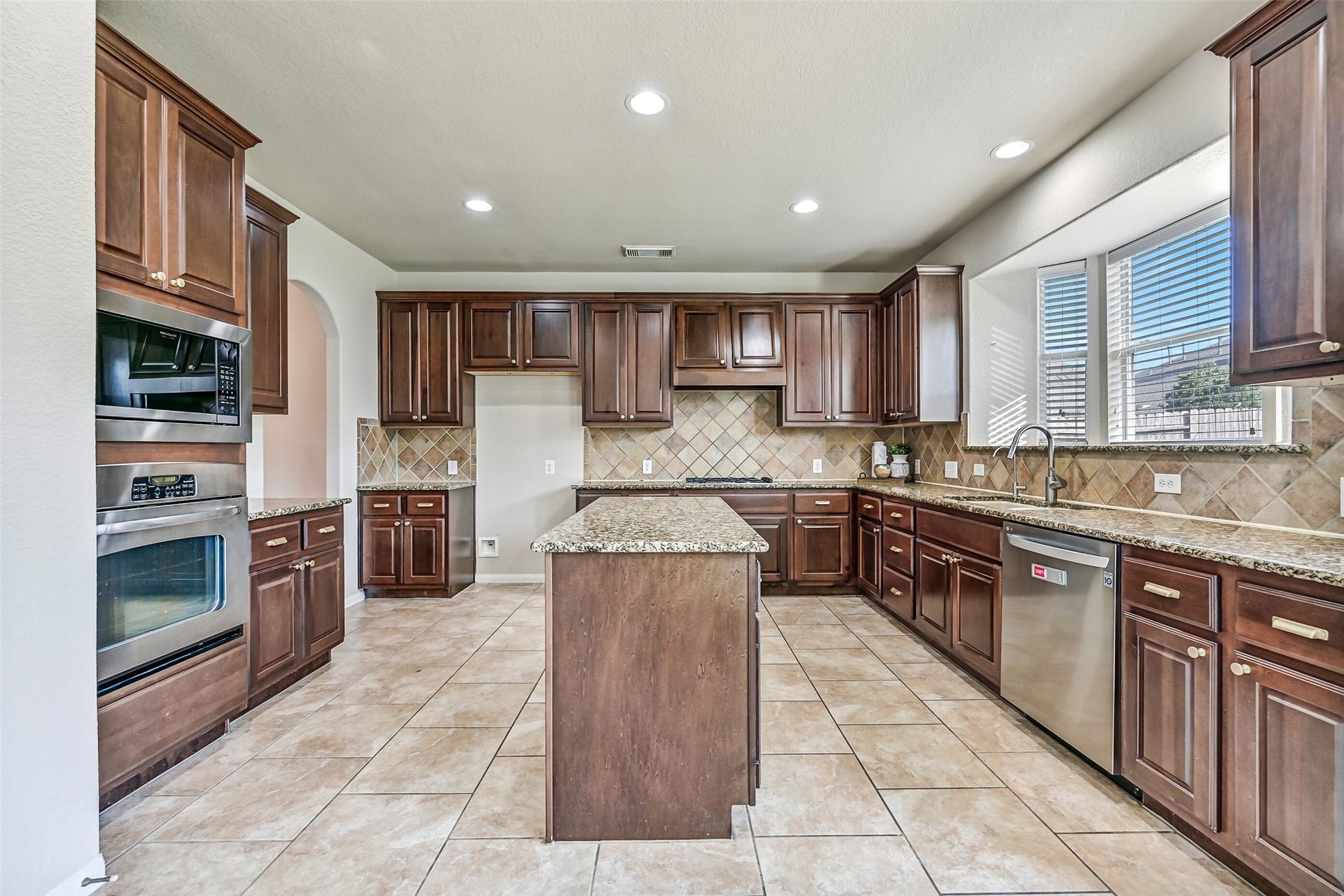 2508 Rockygate Lane, Friendswood, TX 77546 Continue into the heart of the home where this impressively sized island kitchen showcases gleaming granite countertops, a diagonally laid tile backsplash, recessed lighting, and an abundance of richly stained raised-panel cabinetry. The oversized center island provides additional prep space, storage, and a natural gathering spot for family and friends.