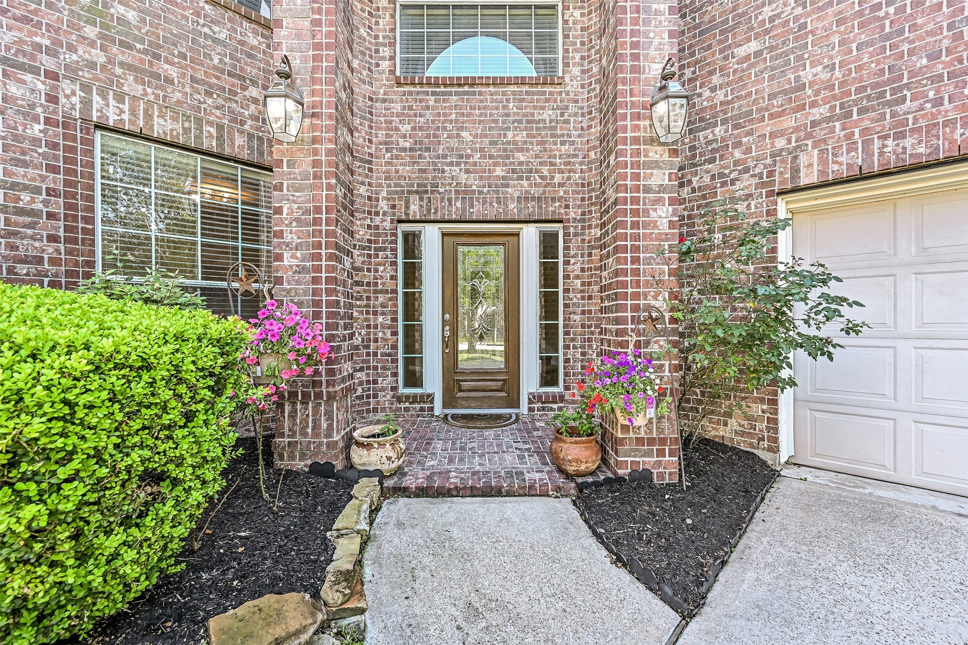 2508 Rockygate Lane, Friendswood, TX 77546 Follow the walkway to the diagonally positioned east-facing front door, tucked beneath a covered entry framed by towering brick columns. Decorative glass inserts, updated landscaping, and colorful seasonal blooms provide a welcoming introduction to the beautiful spaces that await inside.