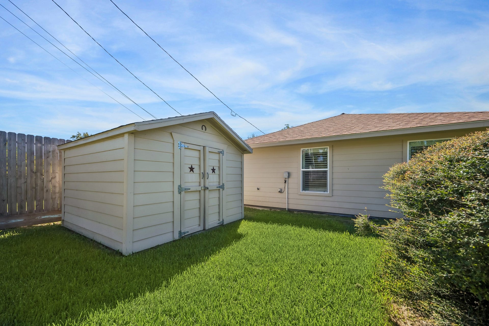 Looking across the backyard from the side of the home, this angle highlights the generous green space, no rear neighbors, and plenty of room for gardening, play equipment, or future outdoor additions.