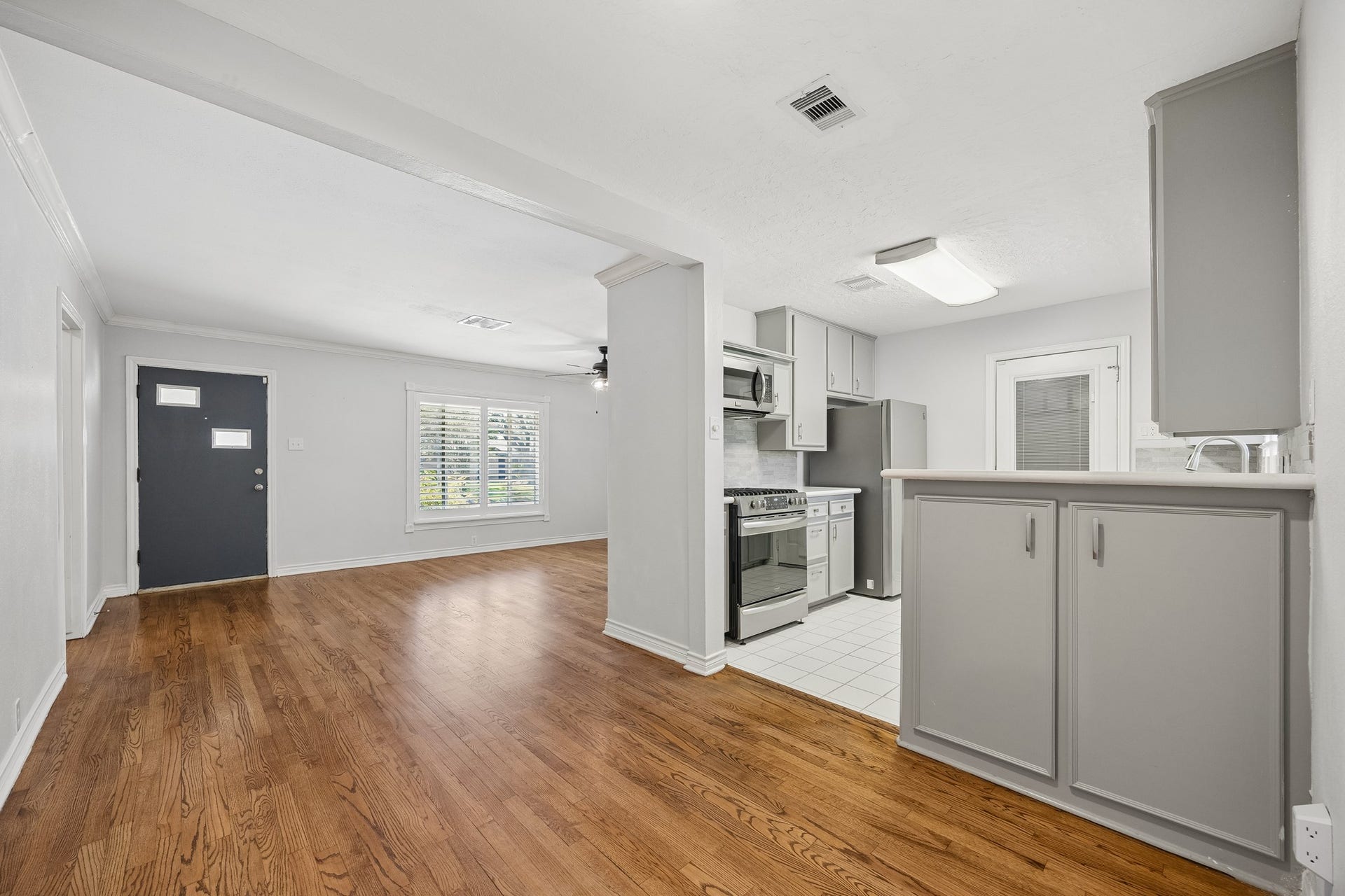 View from the front entry into the spacious living room, highlighting the open layout, hardwood flooring, and natural flow into the adjoining dining space.