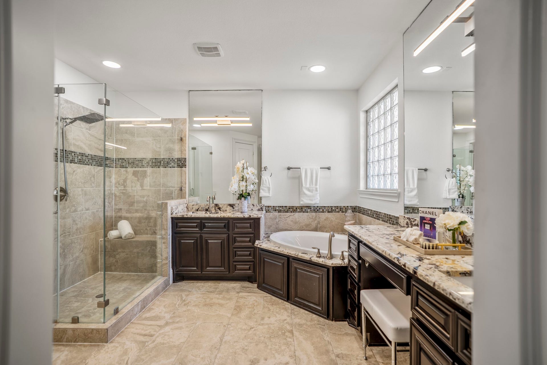 Start and end each day in a spa-like primary bath featuring separate vanity areas, a jetted tub for unwinding, a glass walk-in shower, and a generously sized walk-in closet.
