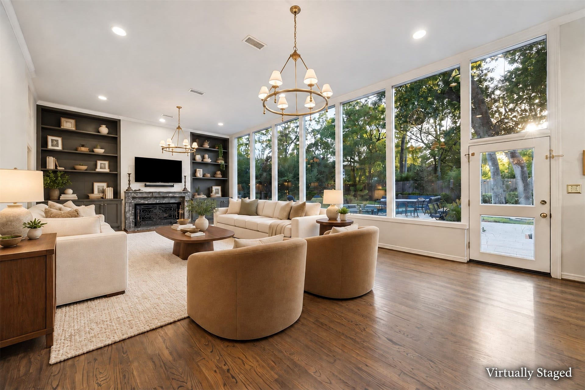 14 Stonegate Drive, Houston, TX 77024 Virtually Staged - Expansive living room with wall of windows offering stunning views of the maturely landscaped backyard complemented by elegant built-in shelving and an oversized fireplace, perfect for relaxing or entertaining.