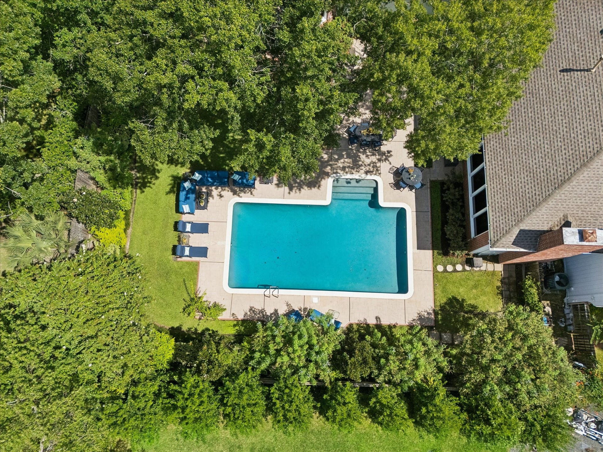 14 Stonegate Drive, Houston, TX 77024 Aerial view of a spacious backyard oasis featuring a large, inviting swimming pool surrounded by lush greenery and ample patio space for relaxation and entertaining.