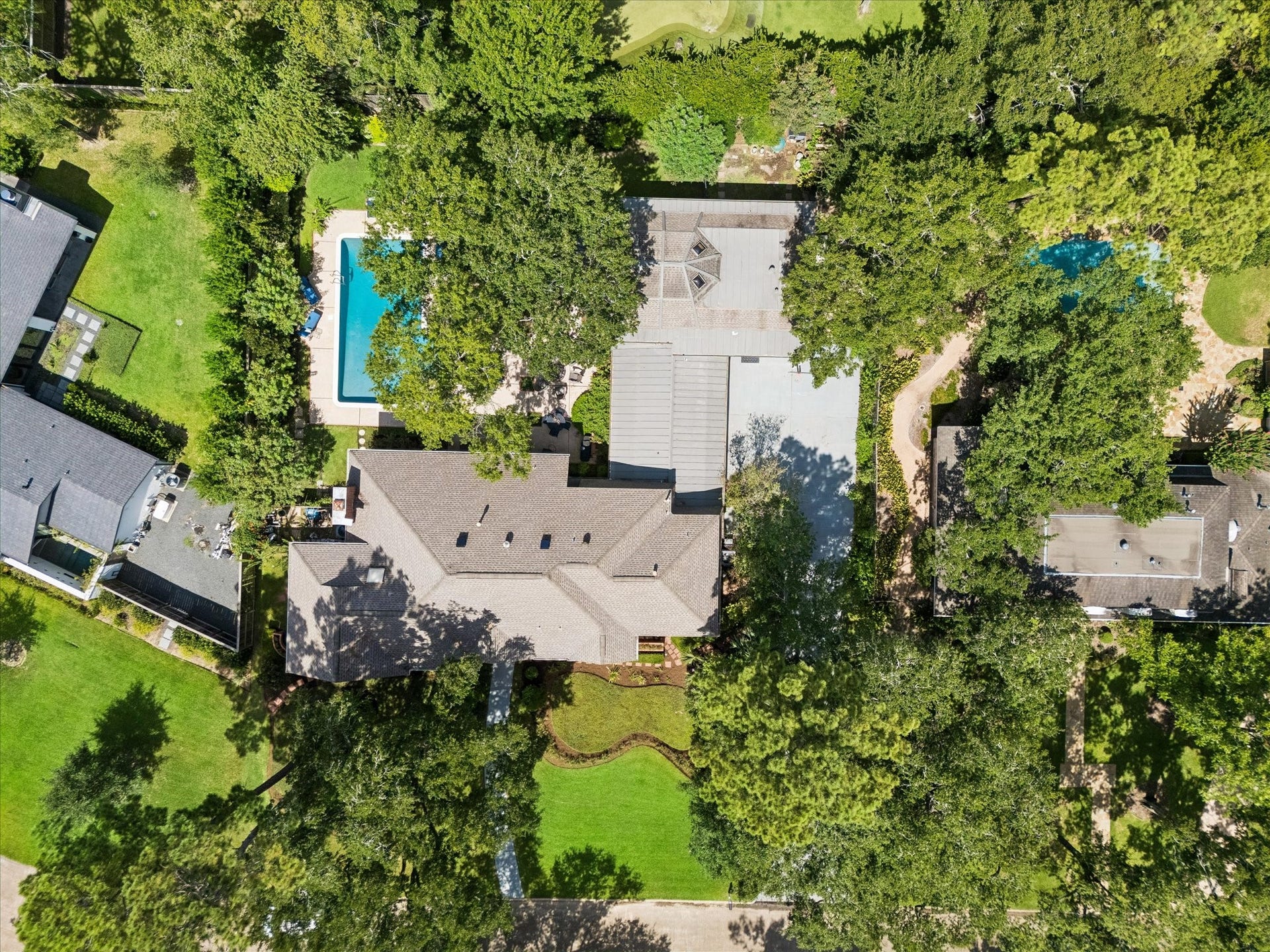 14 Stonegate Drive, Houston, TX 77024 Sprawling estate nestled among lush greenery, featuring a large backyard with a sparkling swimming pool and ample outdoor space for relaxation and entertainment.