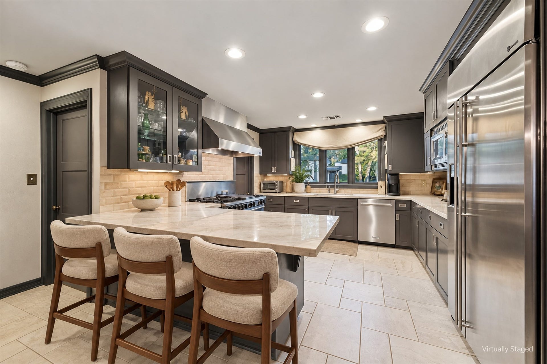 14 Stonegate Drive, Houston, TX 77024 Virtually Staged - Modern kitchen with sleek stainless steel appliances, elegant marble countertops, and ample cabinetry. The layout includes a breakfast bar and a view of the front yard.
