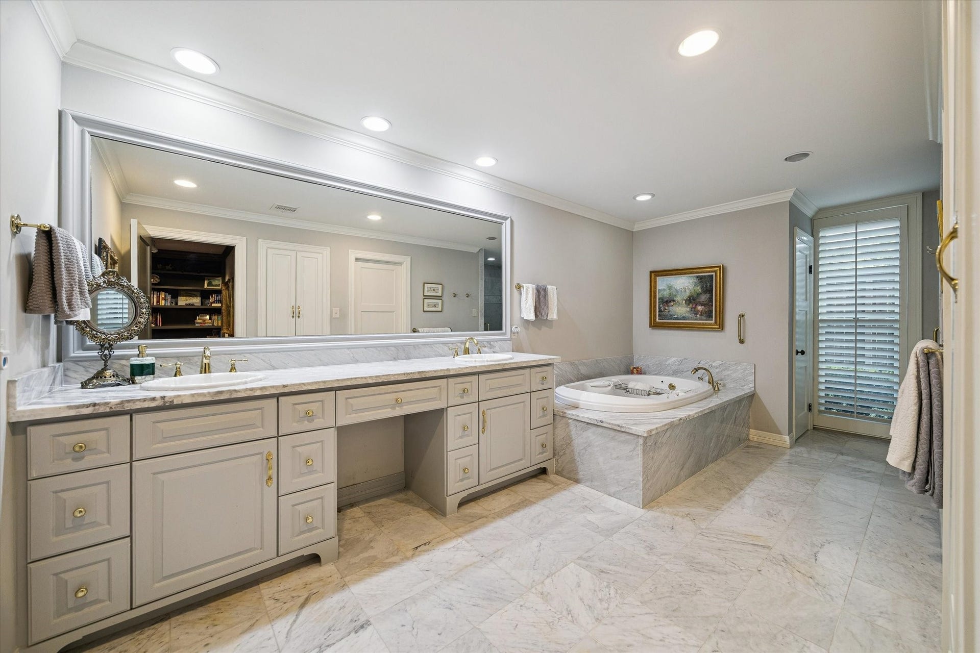 14 Stonegate Drive, Houston, TX 77024 An elegant primary bathroom featuring a spacious double vanity, a relaxing whirlpool tub, and exquisite marble flooring, all bathed in soft, ambient lighting.