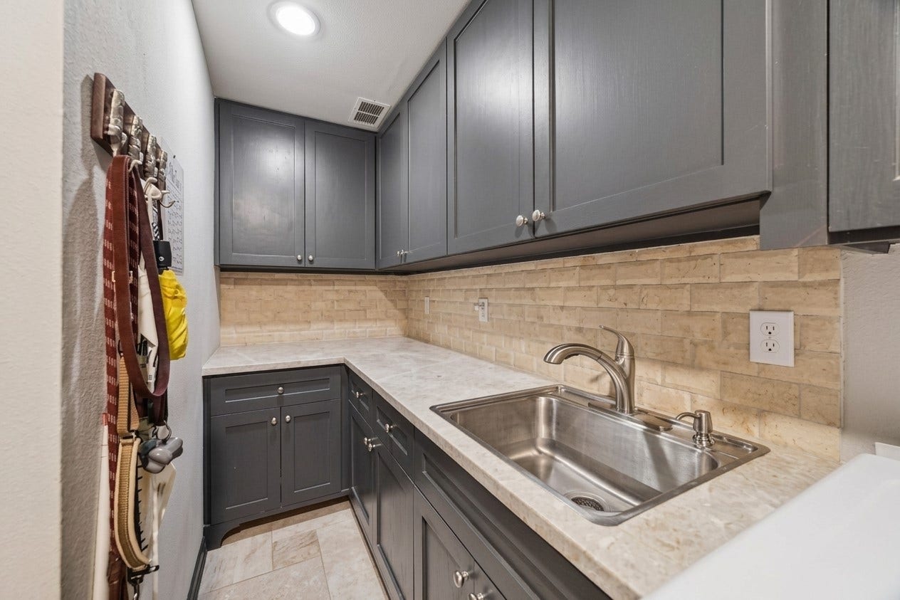 14 Stonegate Drive, Houston, TX 77024 Effortlessly handle chores in this updated utility room, featuring ample storage with shaker cabinetry, a modern sink, and a stylish backsplash for ultimate functionality.