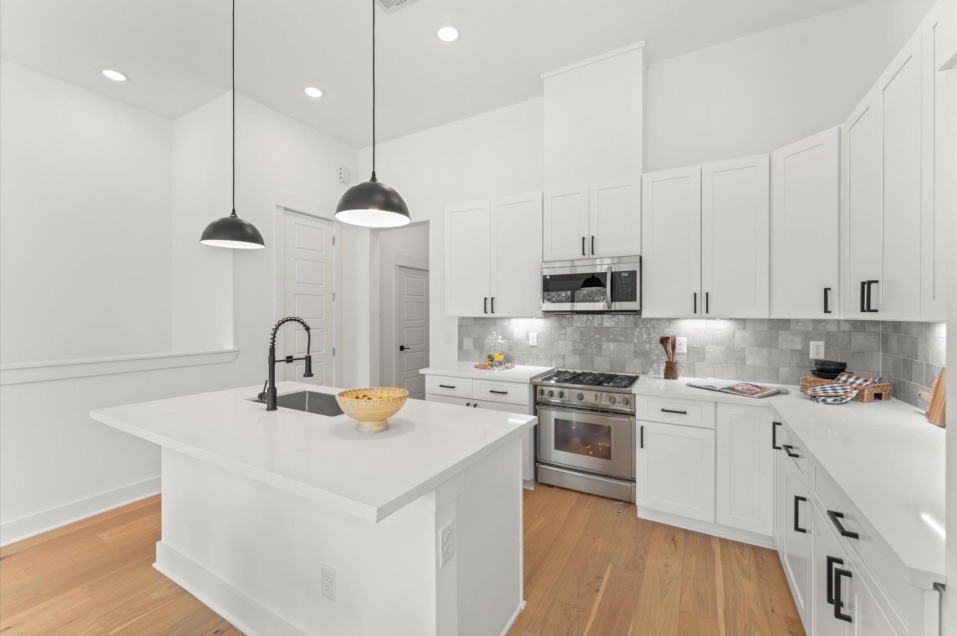 Striking kitchen island serves as the centerpiece of this open-concept space, offering both style and functionality. Topped with sleek quartz, the island includes bar seating for casual dining, ample storage with built-in cabinetry, and a spacious prep surface ideal for entertaining or everyday cooking. Pendant lighting overhead adds a touch of elegance, while the islands placement encourages seamless flow between the kitchen, dining, and living areas.