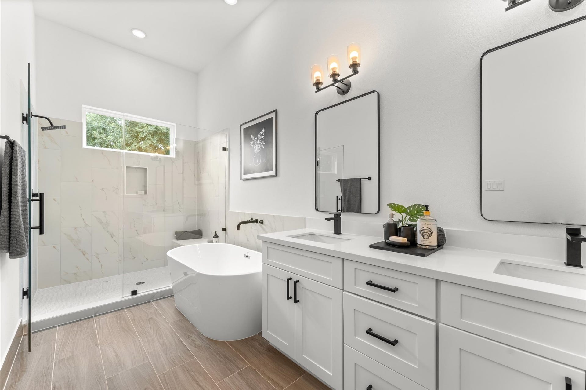Elegant and serene primary bathroom designed to offer both style and functionality. The space features a luxurious soaking tub ideal for unwinding, a separate glass-enclosed shower for quick refreshes, and a sleek double vanity with ample countertop space and storageperfect for busy mornings or relaxing evenings.