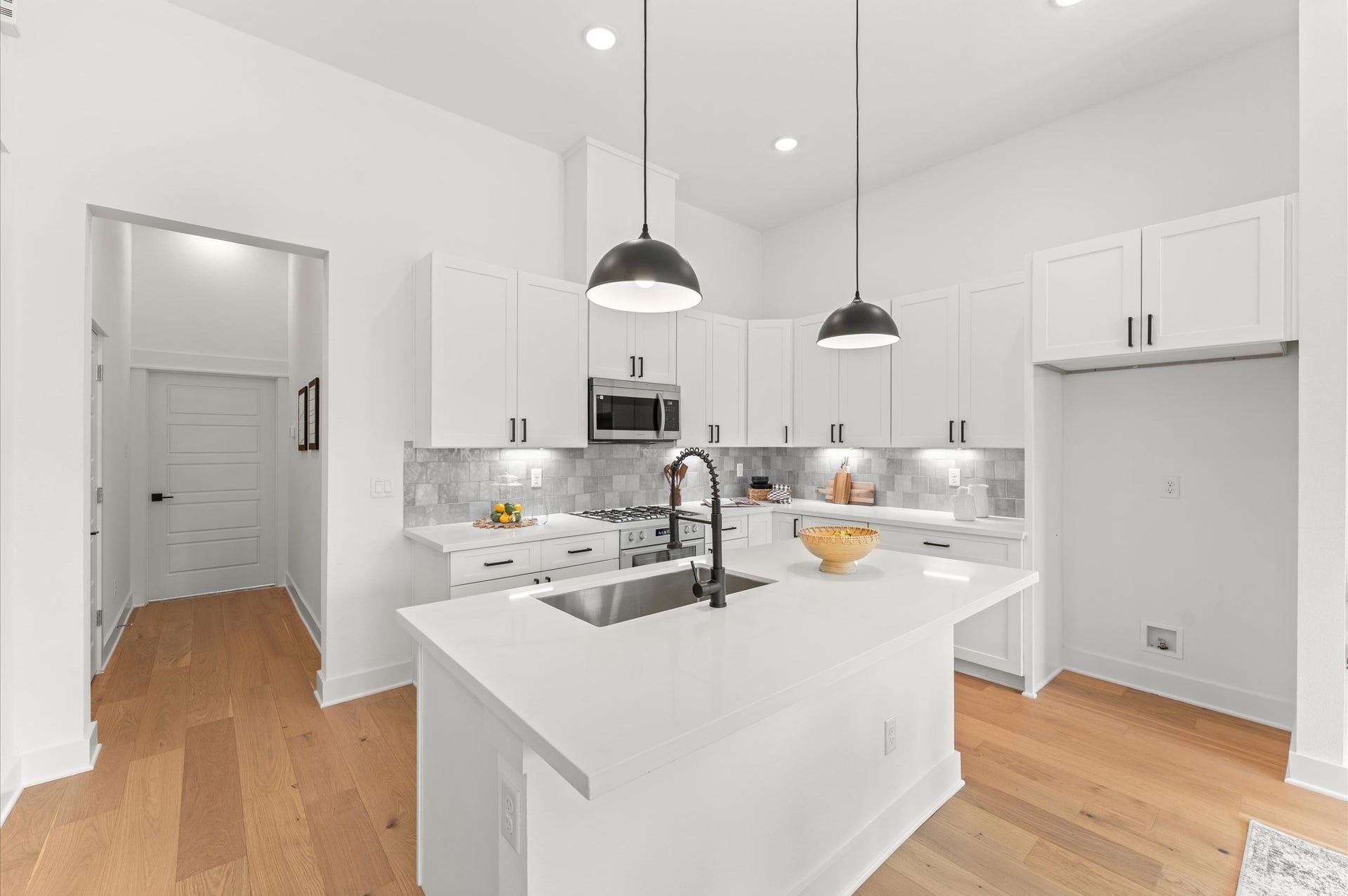 Striking kitchen island serves as the centerpiece of this open-concept space, offering both style and functionality. Topped with sleek quartz, the island includes bar seating for casual dining, ample storage with built-in cabinetry, and a spacious prep surface ideal for entertaining or everyday cooking. Pendant lighting overhead adds a touch of elegance, while the islands placement encourages seamless flow between the kitchen, dining, and living areas.