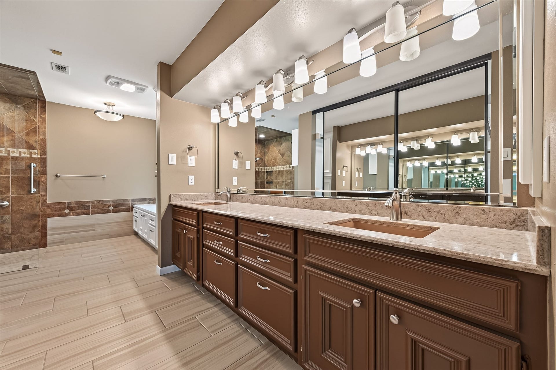 Primary bath is fully updated. Wood look tile floors, lots of lighting and tons of cabinet space for storage.