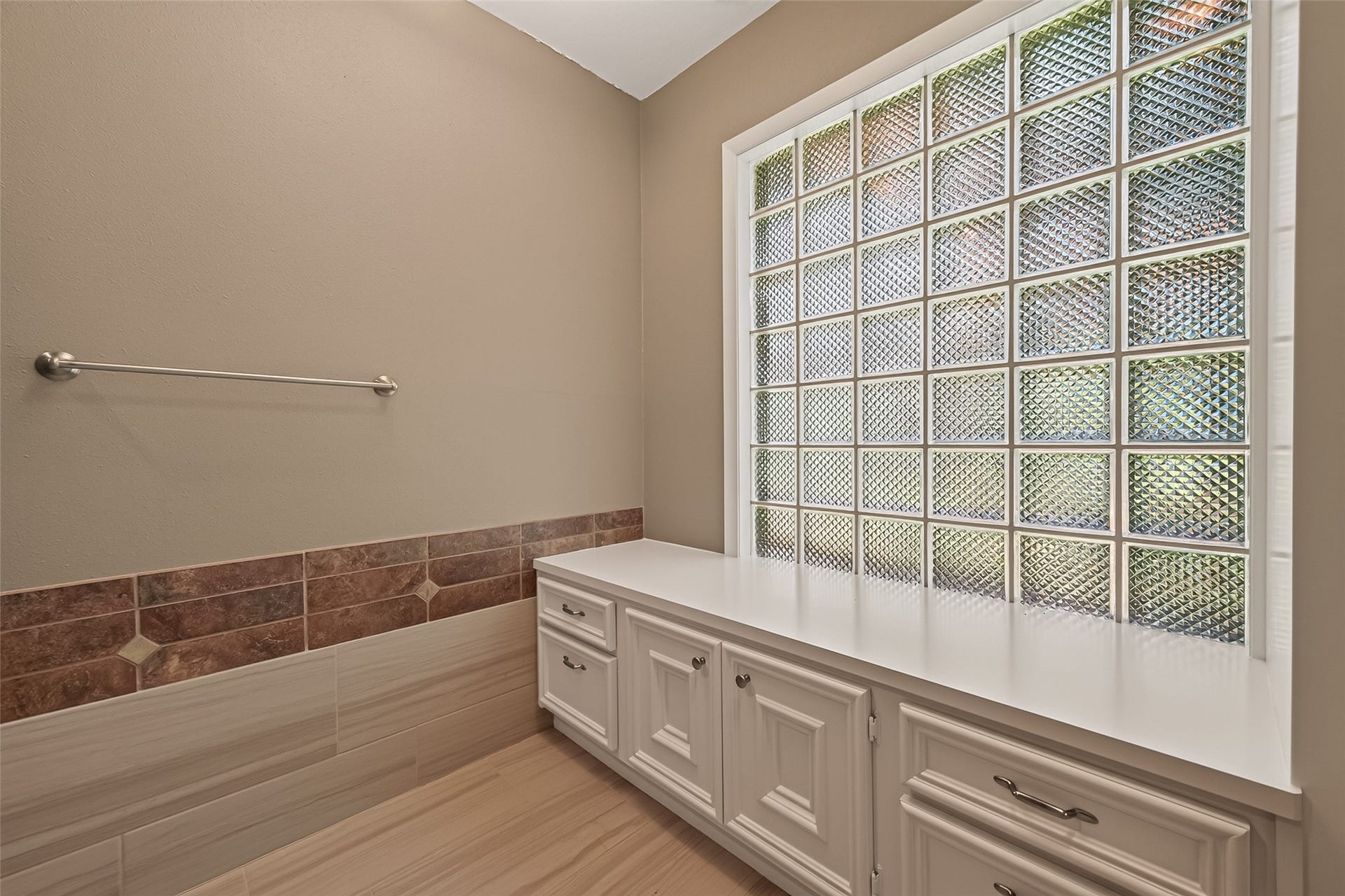 Built in cabinets with glass block wall allows light to filter into the primary bathroom area while preserving privacy.