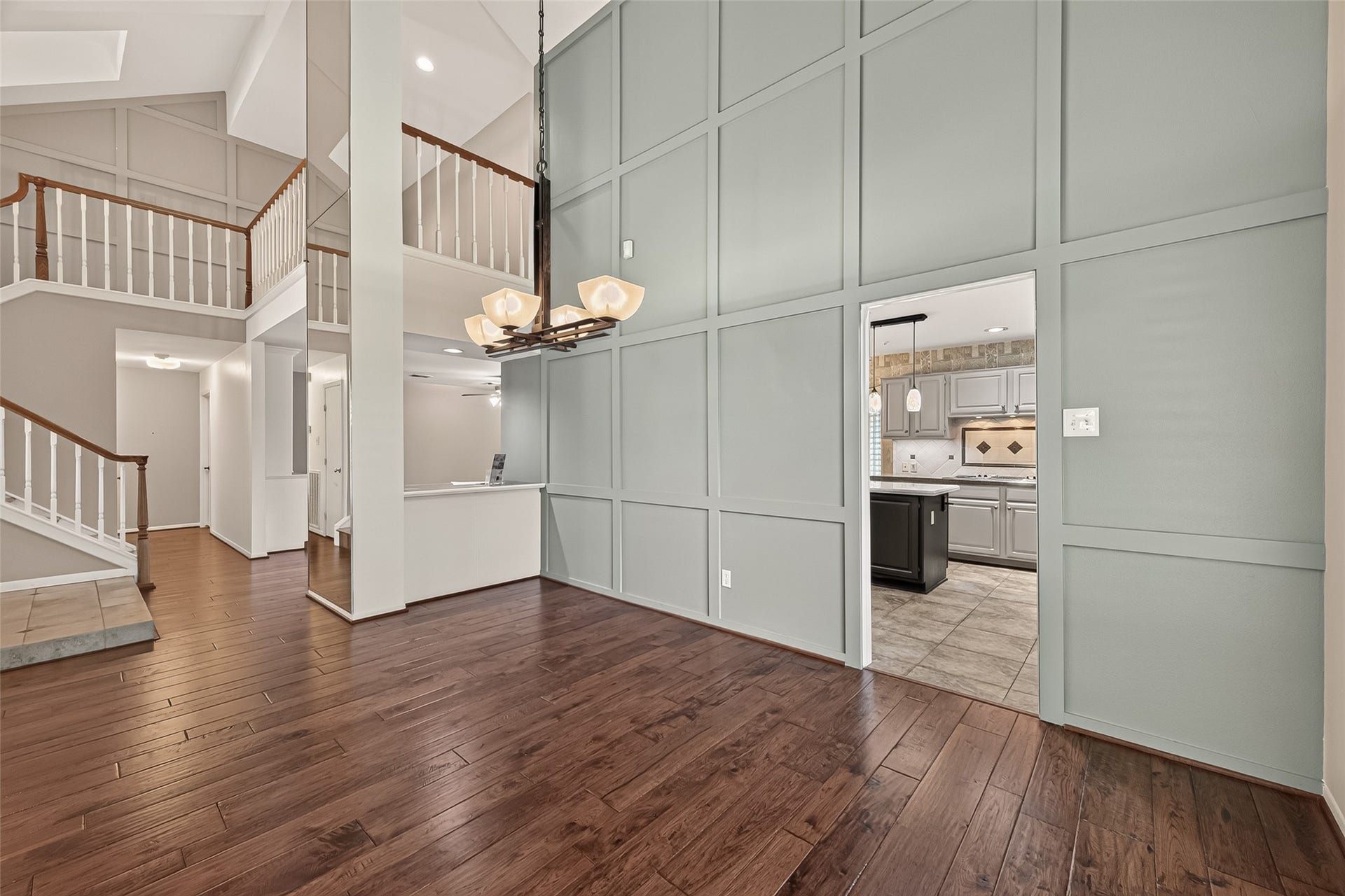 Beautifully designed open-concept home featuring soaring ceilings, rich hardwood floors, and a striking paneled accent wall. The layout flows seamlessly from the grand entry to the kitchen, creating a bright and inviting space perfect for entertaining or everyday living. Elegant architectural details and modern finishes add timeless appeal throughout.