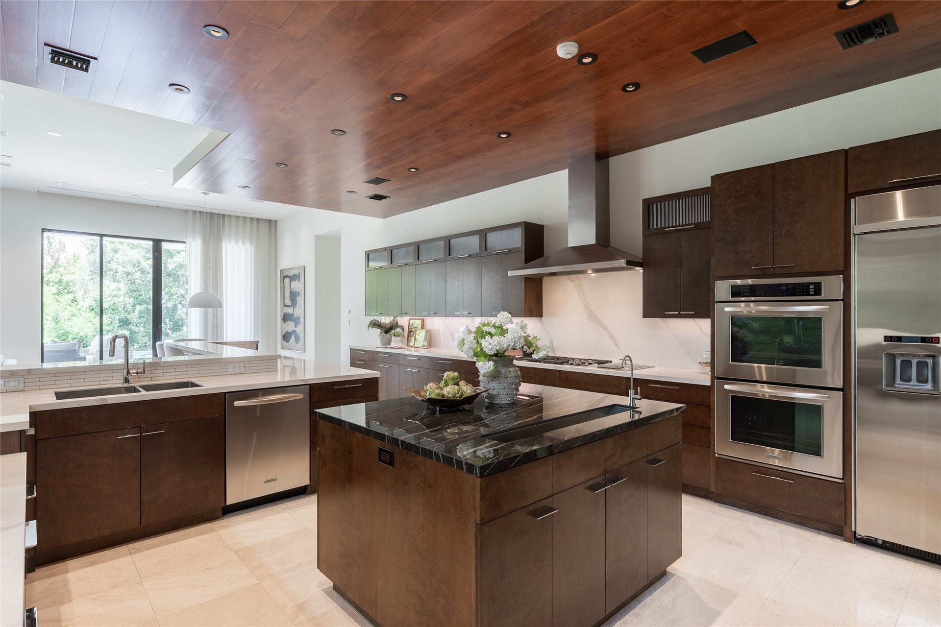 309 Glenwood Drive, Houston, TX 77007 At the center of the kitchen, a dedicated prep island incorporates a linear sink and contrasting dark countertop, creating a striking counterpoint to the lighter porcelain surfaces surrounding it.