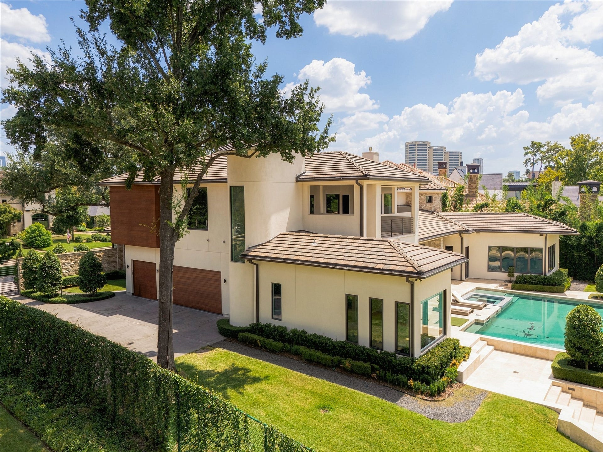 309 Glenwood Drive, Houston, TX 77007 The architecture unfolds beyond the front elevation, with clean geometric forms, warm mahogany accents and mature landscaping creating a more private side of the residence. Generous setbacks allow the home to feel substantial without sacrificing openness, greenery or privacy.