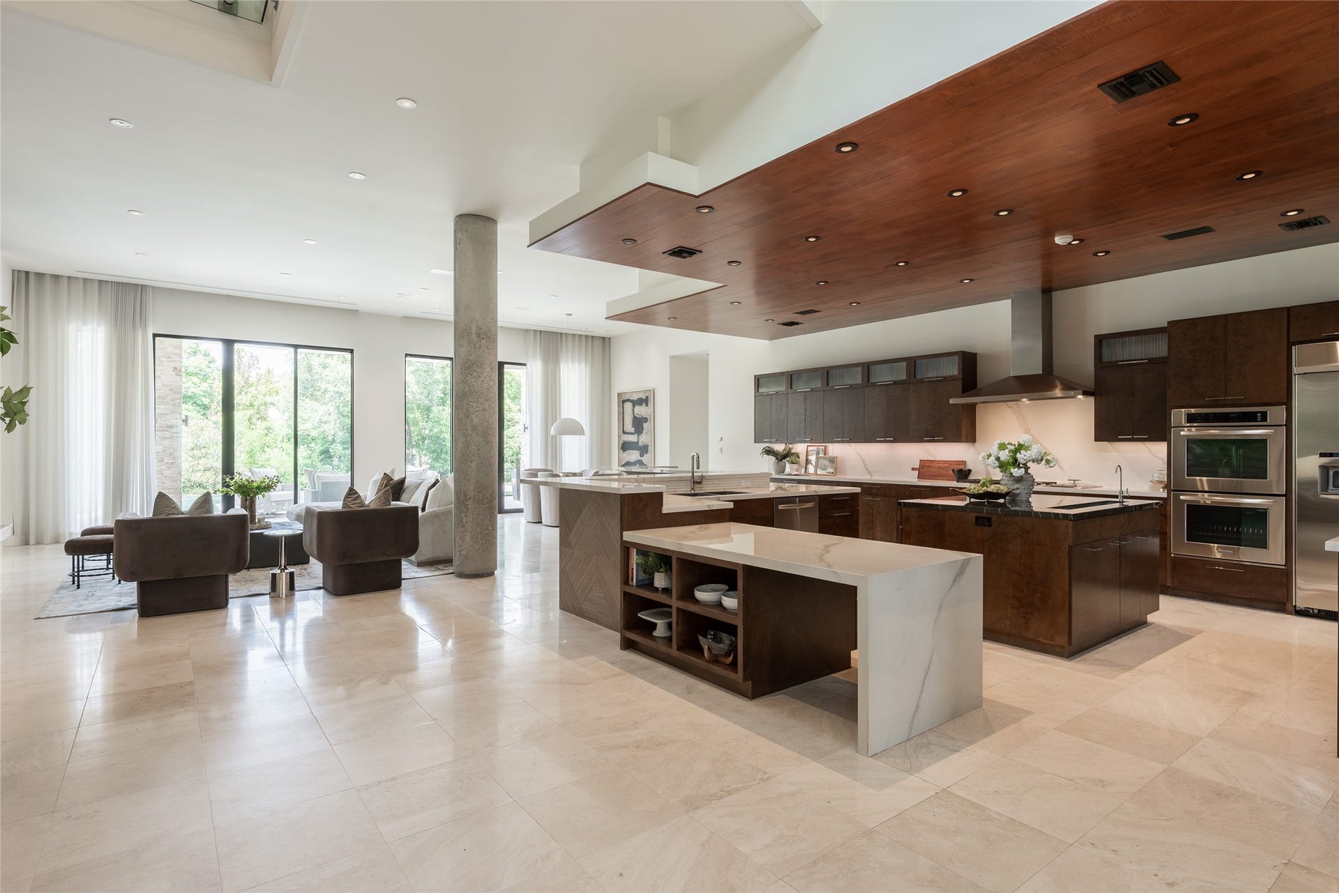 309 Glenwood Drive, Houston, TX 77007 A suspended ceiling creates an architectural canopy over the kitchen, visually defining the space without separating it from the surrounding living areas. Custom cabinetry continues the material palette below, giving the kitchen a warmth and richness that contrasts beautifully against the homes lighter finishes