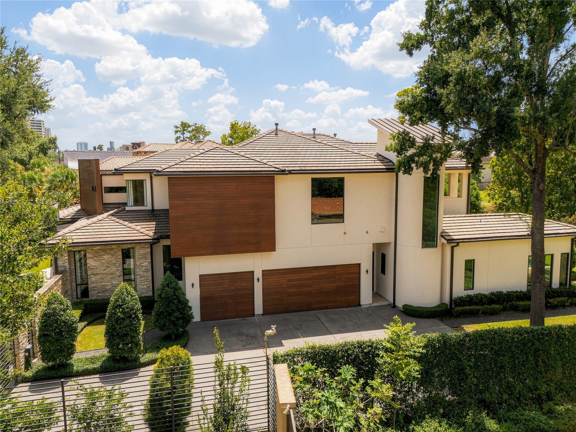 309 Glenwood Drive, Houston, TX 77007 The side elevation reveals the homes material driven architecture, where rich mahogany accents, three-coat traditional hard-coat stucco, stacked stone and a natural slate roof create a warm contrast of texture and form.