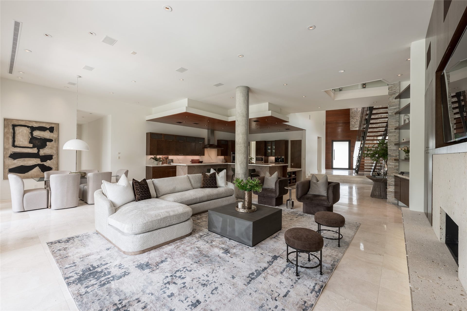 309 Glenwood Drive, Houston, TX 77007 The main living room opens with impressive scale, where soaring ceilings and walls of glass behind fill the space with natural light. A prominent structural concrete column becomes an architectural feature rather than something concealed, adding a distinctive contrast to the homes warmer materials while helping define the transition between the living and kitchen spaces.