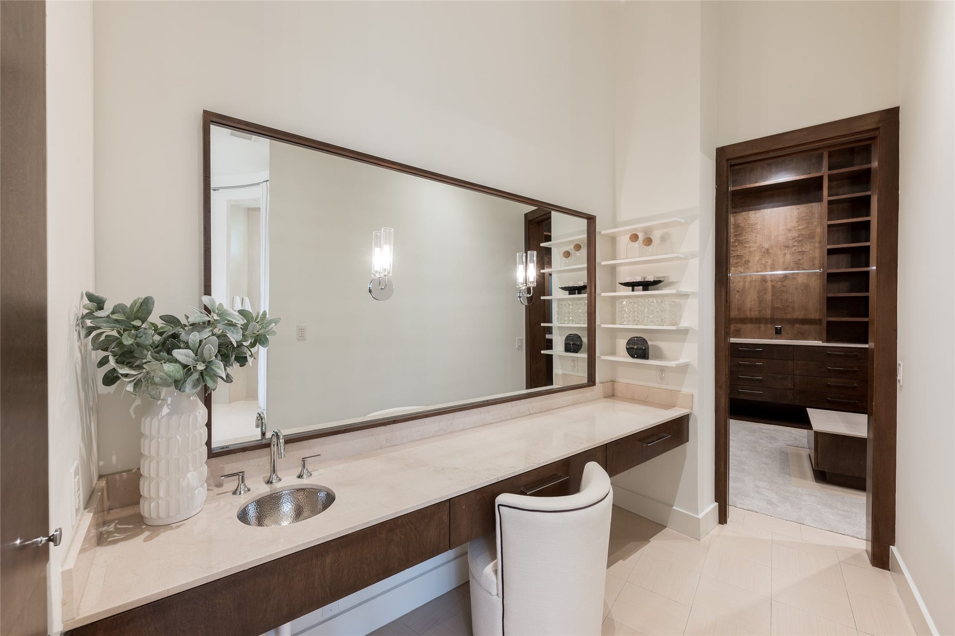 309 Glenwood Drive, Houston, TX 77007 A dedicated vanity within the primary ensuite provides its own defined space, featuring custom floating cabinetry, an expansive mirror and sconces. The generous counter surface and floating shelves keep the area both functional and refined.