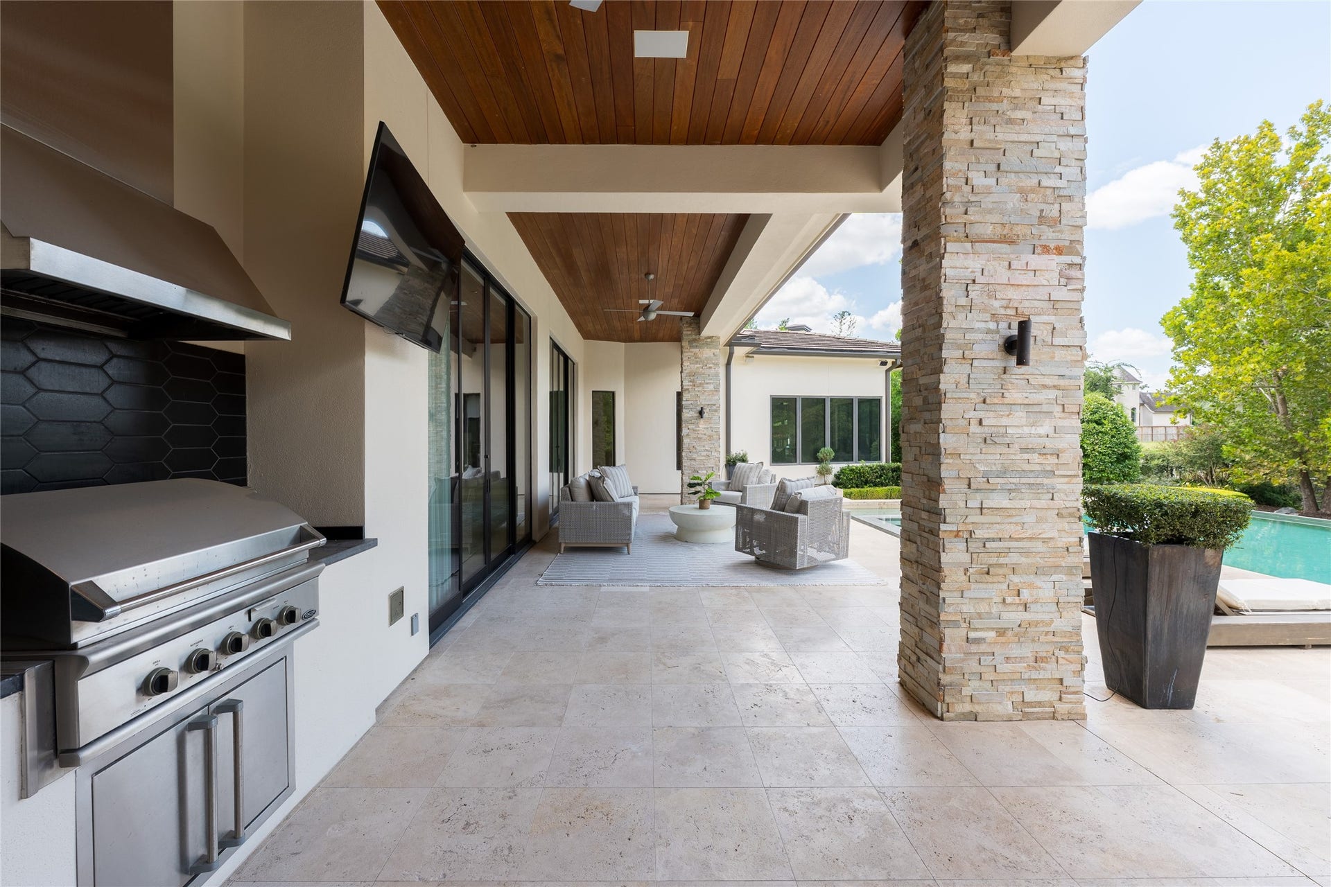 309 Glenwood Drive, Houston, TX 77007 The covered outdoor living area features a full summer kitchen beneath a mahogany tongue-and-groove ceiling, while the homes travertine flooring continues outdoors for a seamless transition in materials. Positioned alongside the pool, the space is designed for year-round cooking, dining and entertaining.