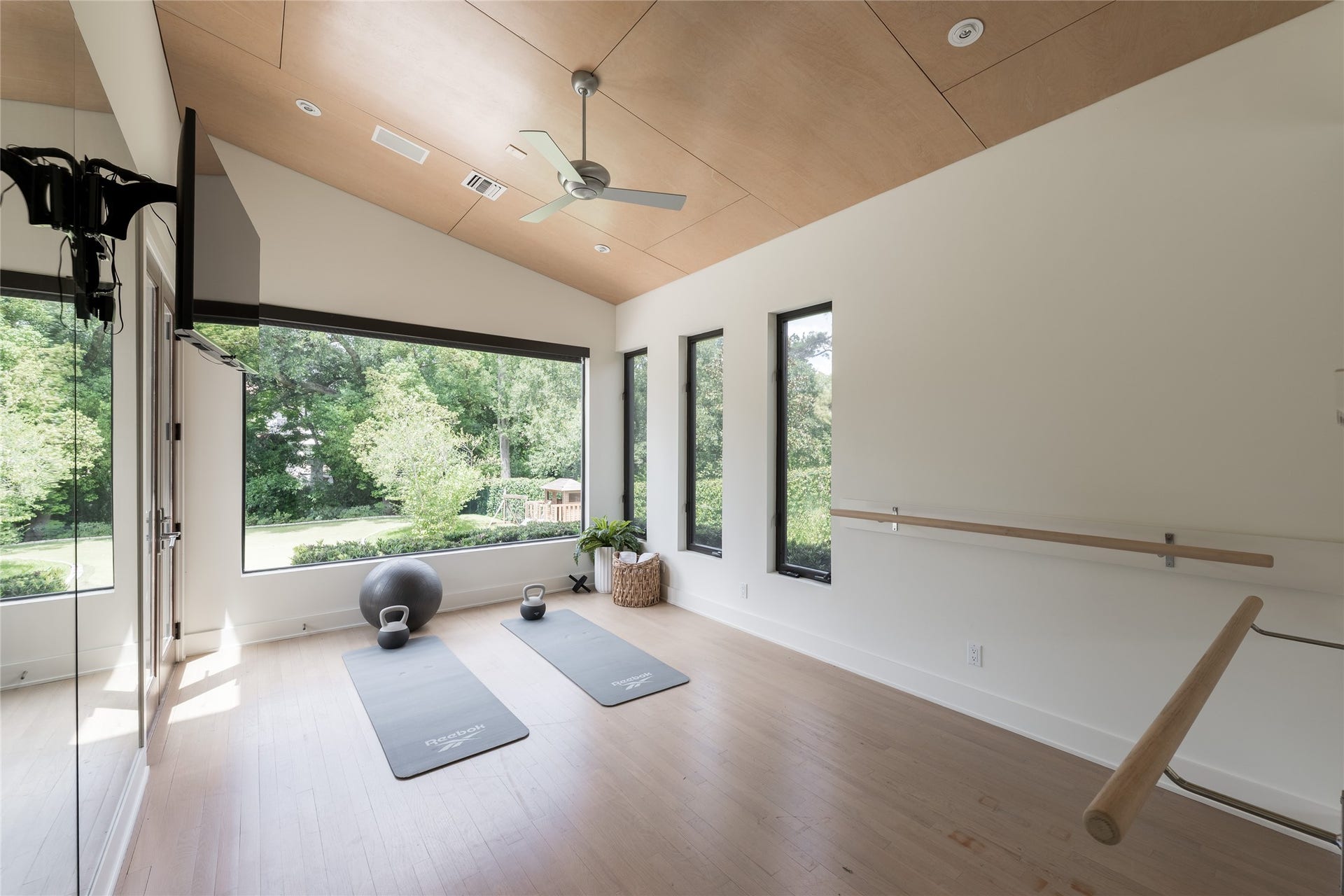 309 Glenwood Drive, Houston, TX 77007 A dedicated wellness studio offers space for yoga, stretching or private training, complete with a built-in ballet barre and mirrored wall. Oversized windows frame views of the backyard and putting green, while the wood-paneled ceiling adds warmth to the light-filled space.