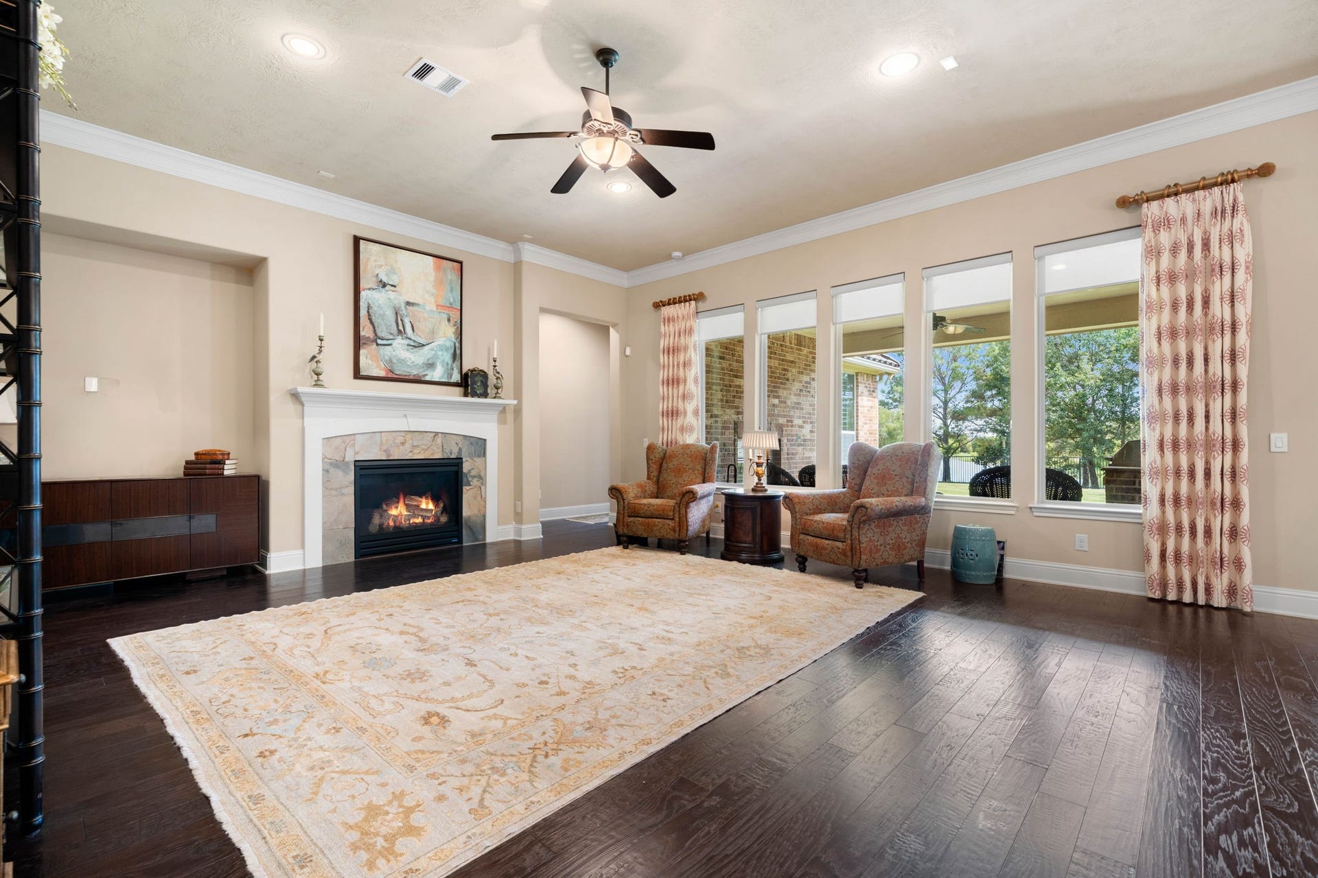 34 Edgemont Court, Fulshear, TX 77441 The living room centers around a cozy gas log fireplace, framed by high ceilings and a wall of windows that fill the space with natural light.