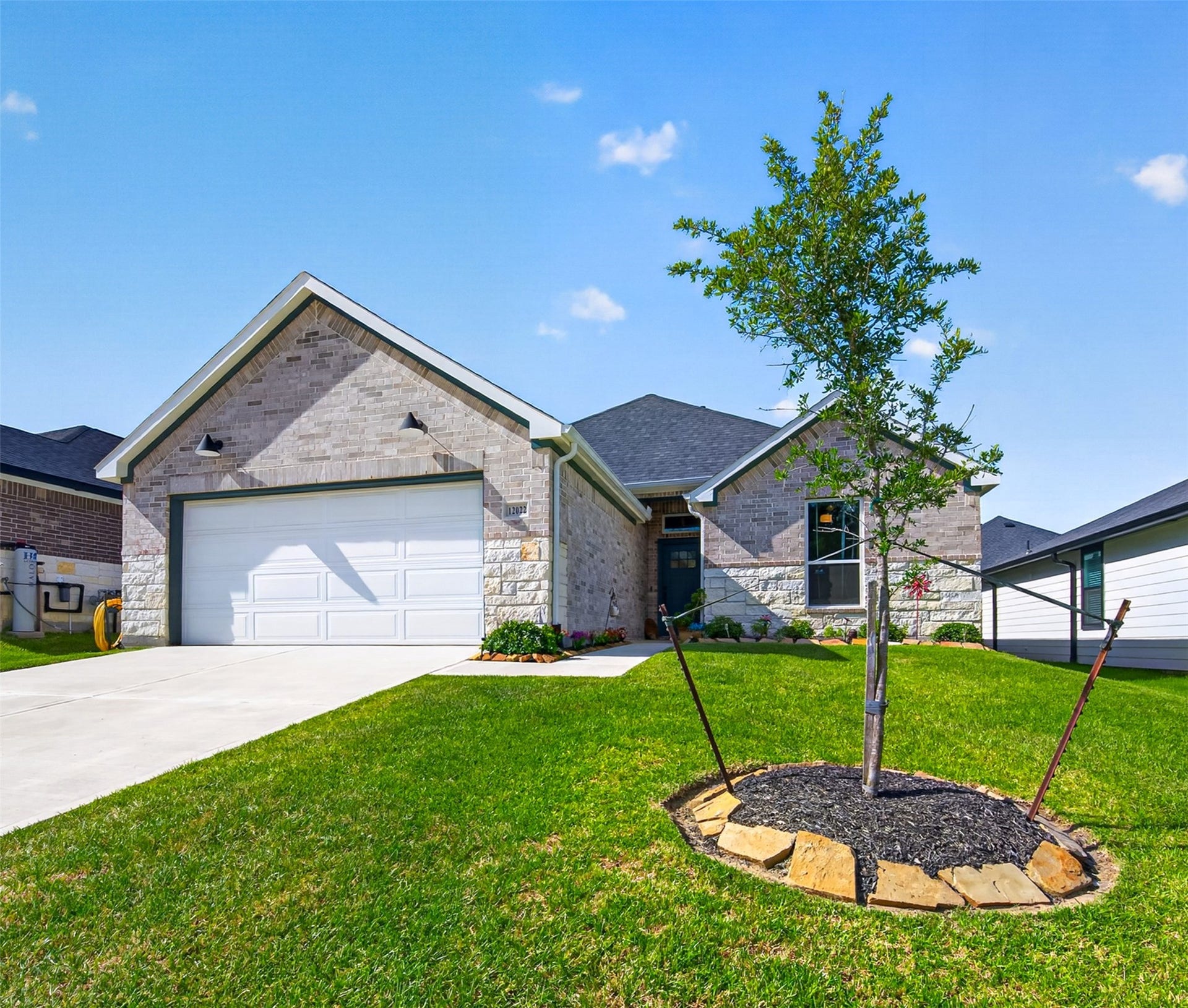 Double Driveway with a 3 Car Tandem Garage and Stone-Brick with a covered entry with gutters.  It's hard to find a 3 Car Garage at this price!  Call Today!