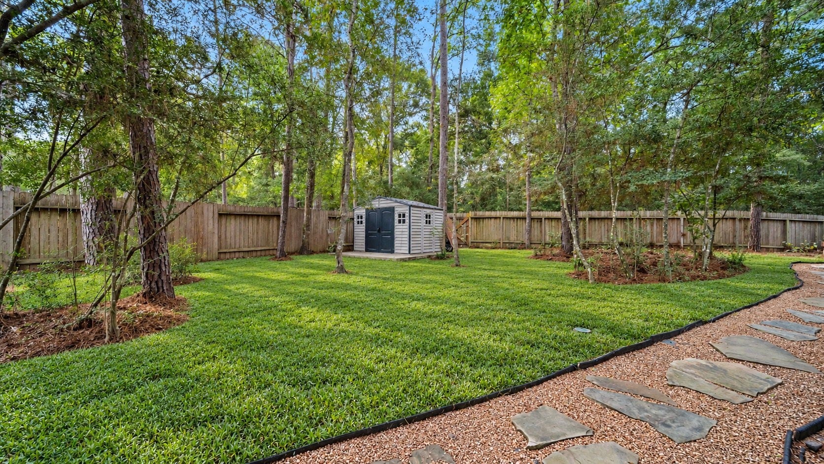 4170 Hidden Timbers Lane, Conroe, TX 77304 A little slice of nature right at home! This beautifully maintained backyard features mature shade trees, lush green grass, and a charming stepping-stone pathway. Shed included for landscaping equipment storage.