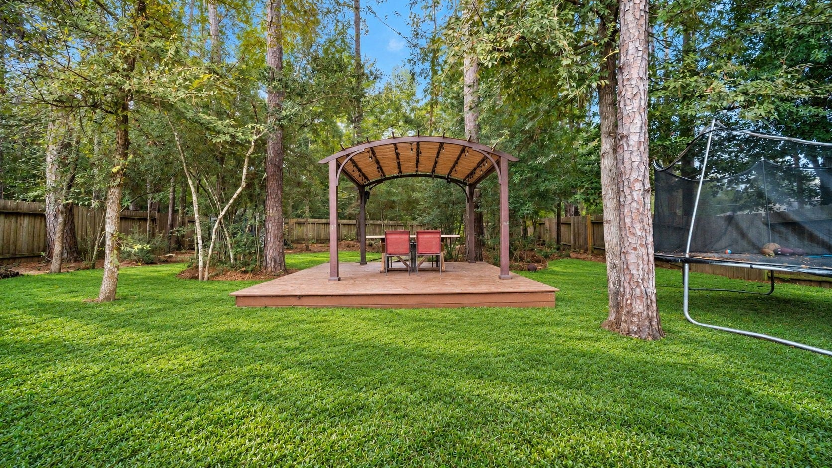 4170 Hidden Timbers Lane, Conroe, TX 77304 Imagine relaxing beneath the trees! This inviting backyard features a raised deck with a pergola, creating a wonderful space for outdoor dining or enjoying a peaceful evening. Outdoor furniture and trampoline not included.
