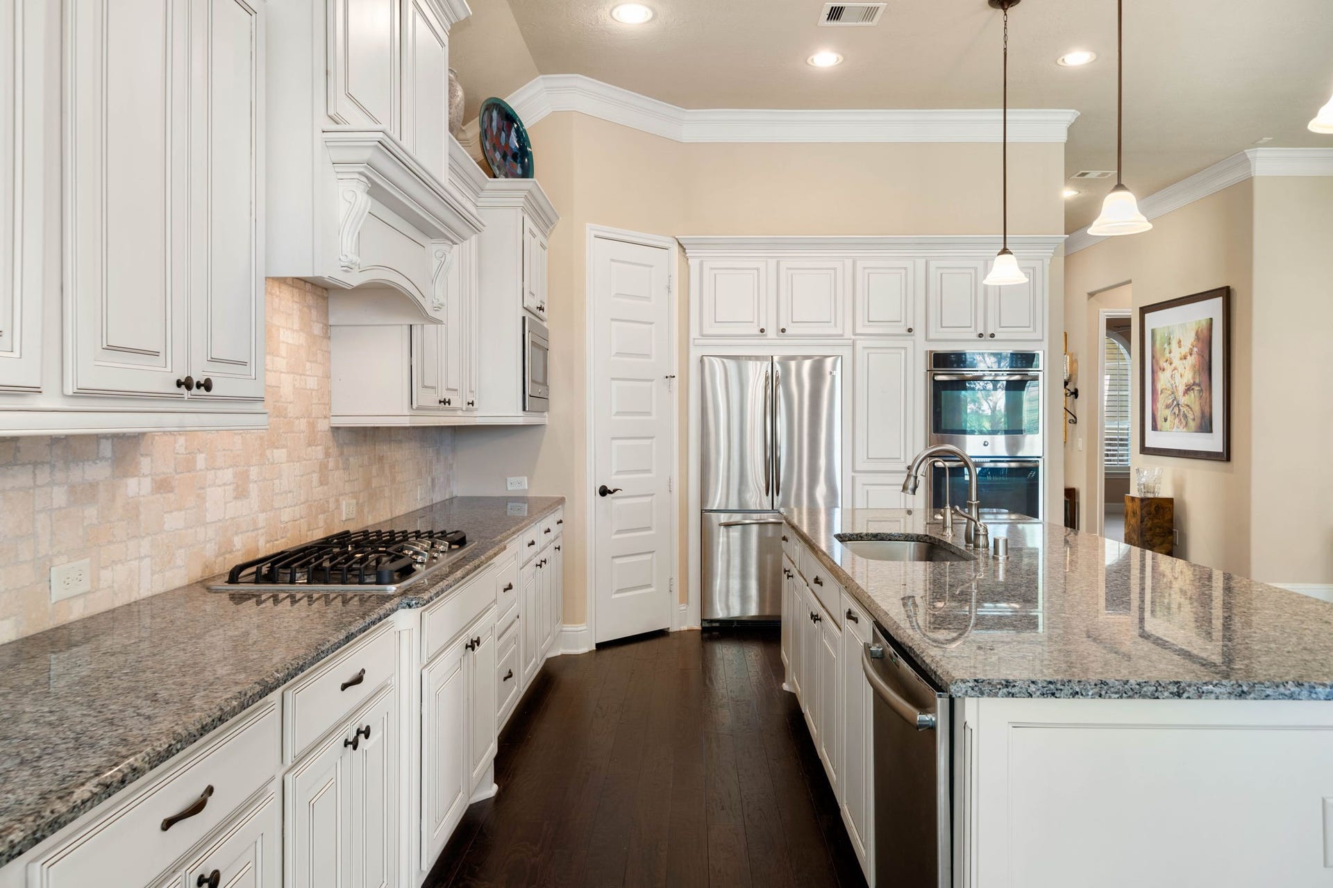 34 Edgemont Court, Fulshear, TX 77441 Soft-close cabinetry, a stone backsplash, and a gas cooktop bring both style and function to this well-appointed kitchen.