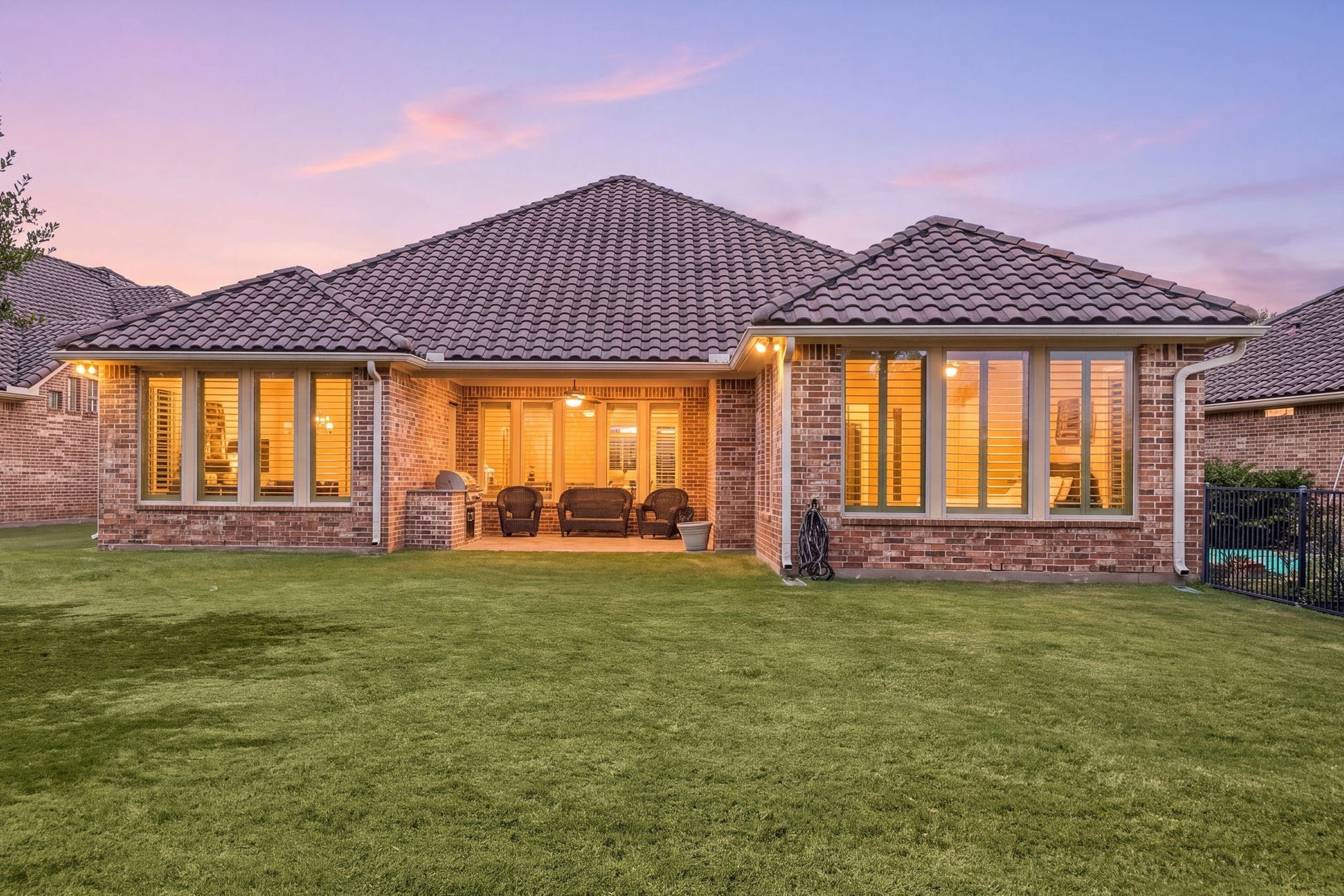 34 Edgemont Court, Fulshear, TX 77441 As evening falls, the home's warm lighting and covered patio create an inviting space to unwind outdoors.