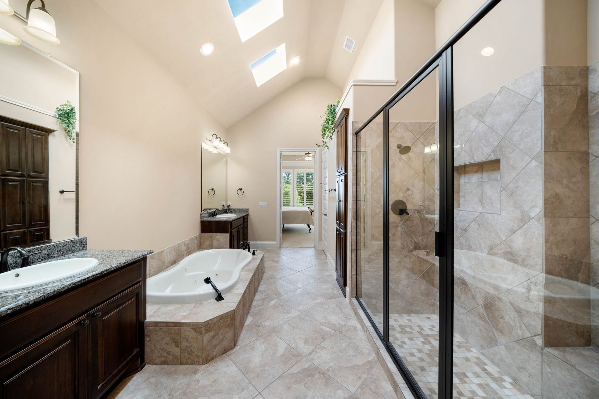 34 Edgemont Court, Fulshear, TX 77441 A separate walk-in shower and vaulted ceiling with skylights bring in natural light and add a sense of openness to the primary bath.